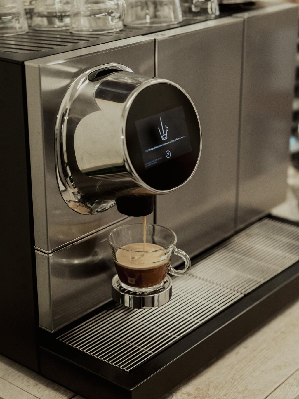 Een zilveren koffiemachine zet een vers kopje espresso in een glas